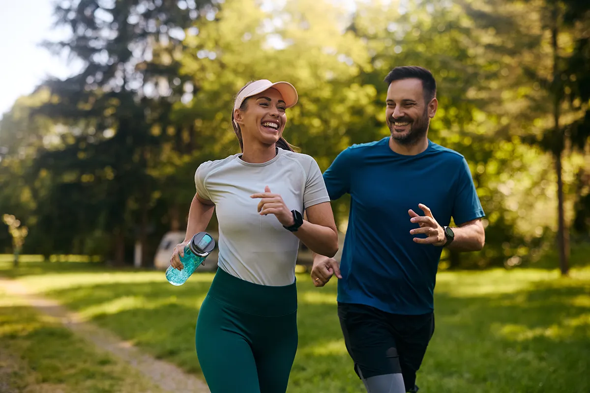 a woman and man running outside in a park